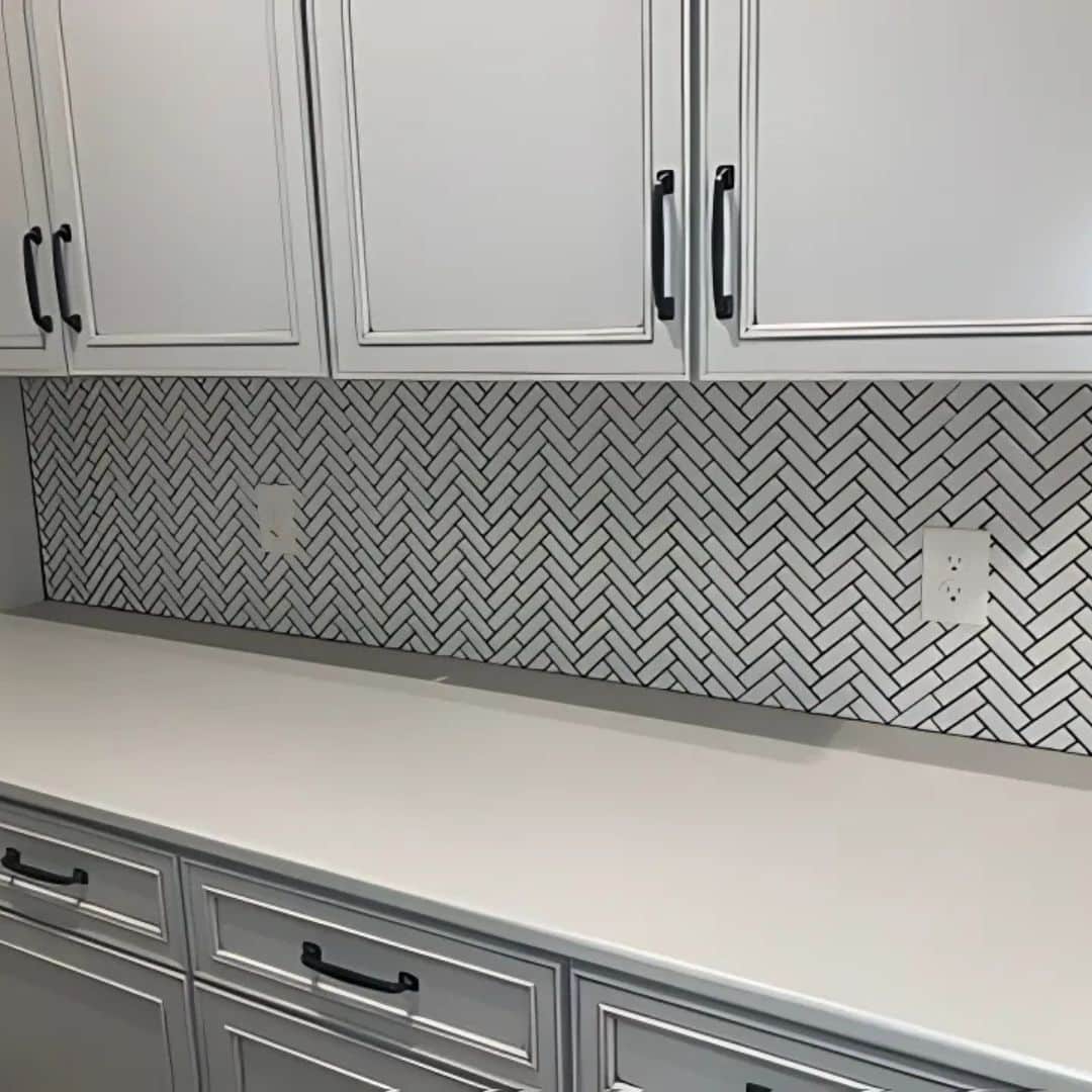 White cabinets and a countertop with a patterned backsplash as part of a kitchen remodeling project.